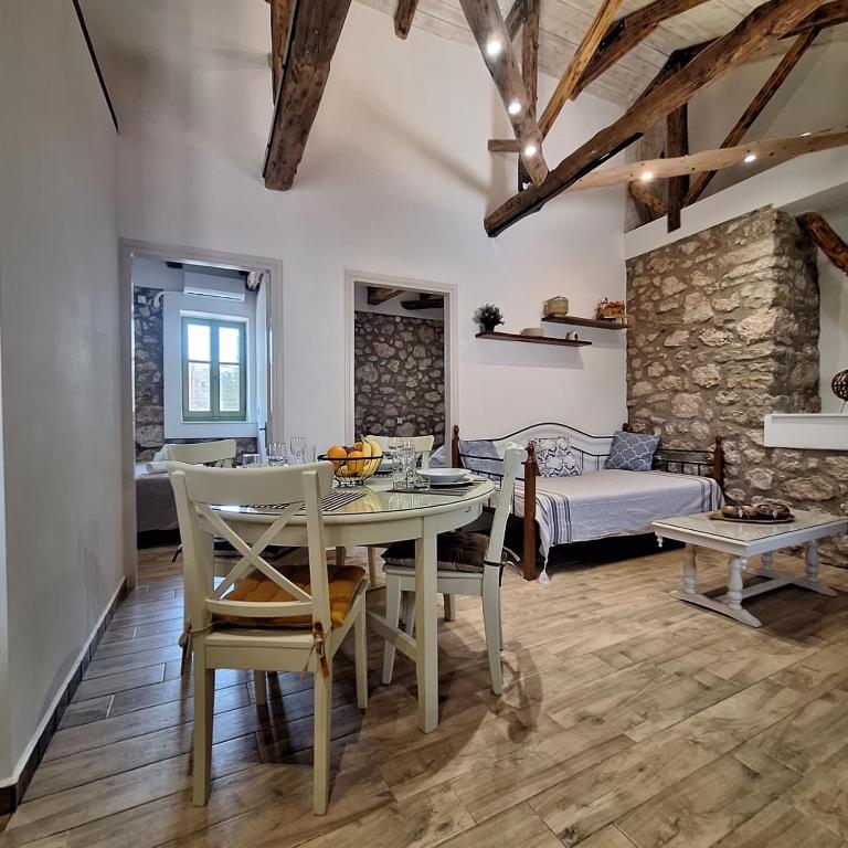 a living room with a table and chairs and a bed at Alekos Cozy Stone 2BR Home Karya Center in Lefkada