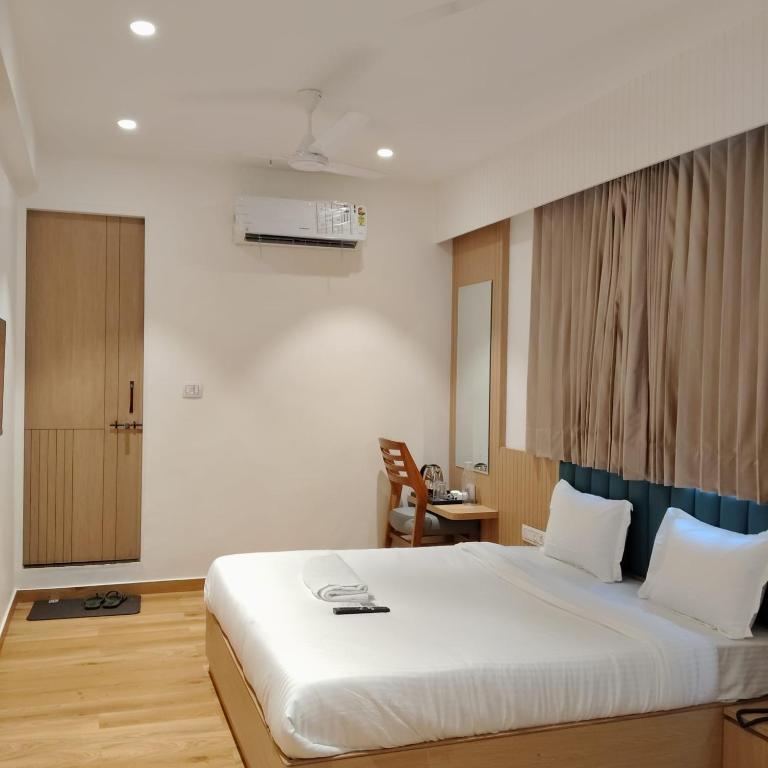 a bedroom with a large white bed and a chair at Hotel Sun City in Kalol