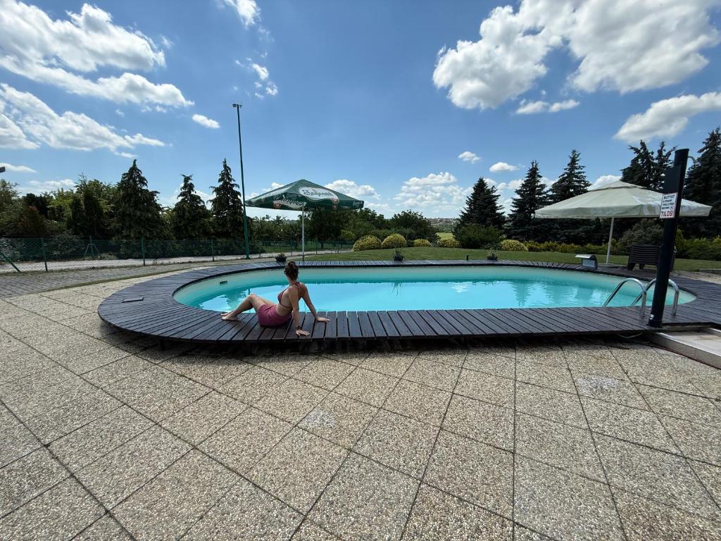 a woman is sitting next to a swimming pool at Az Idill in Cserszegtomaj