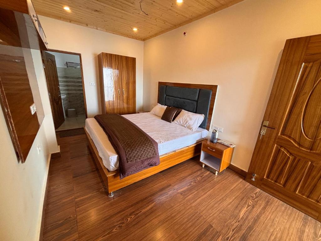 a bedroom with a bed and a wooden floor at Forest Breeze Homestay in Kanatal