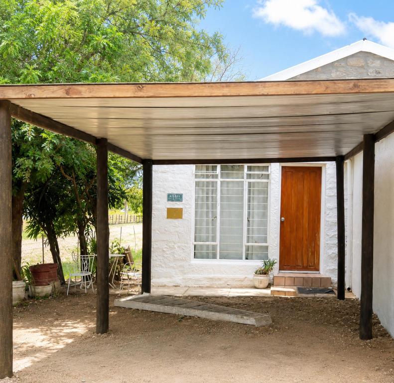 a small white house with a wooden door at Alpha Self-Catering in Sutherland