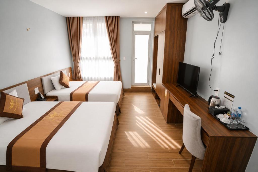 a hotel room with two beds and a television at Eagle Sầm Sơn Hotel in Sầm Sơn