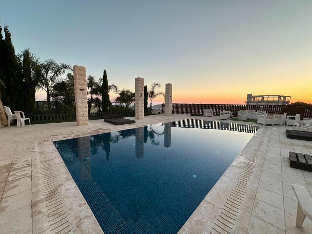 a swimming pool with chairs and a sunset in the background at carmel cabins suite 3 in Yājur