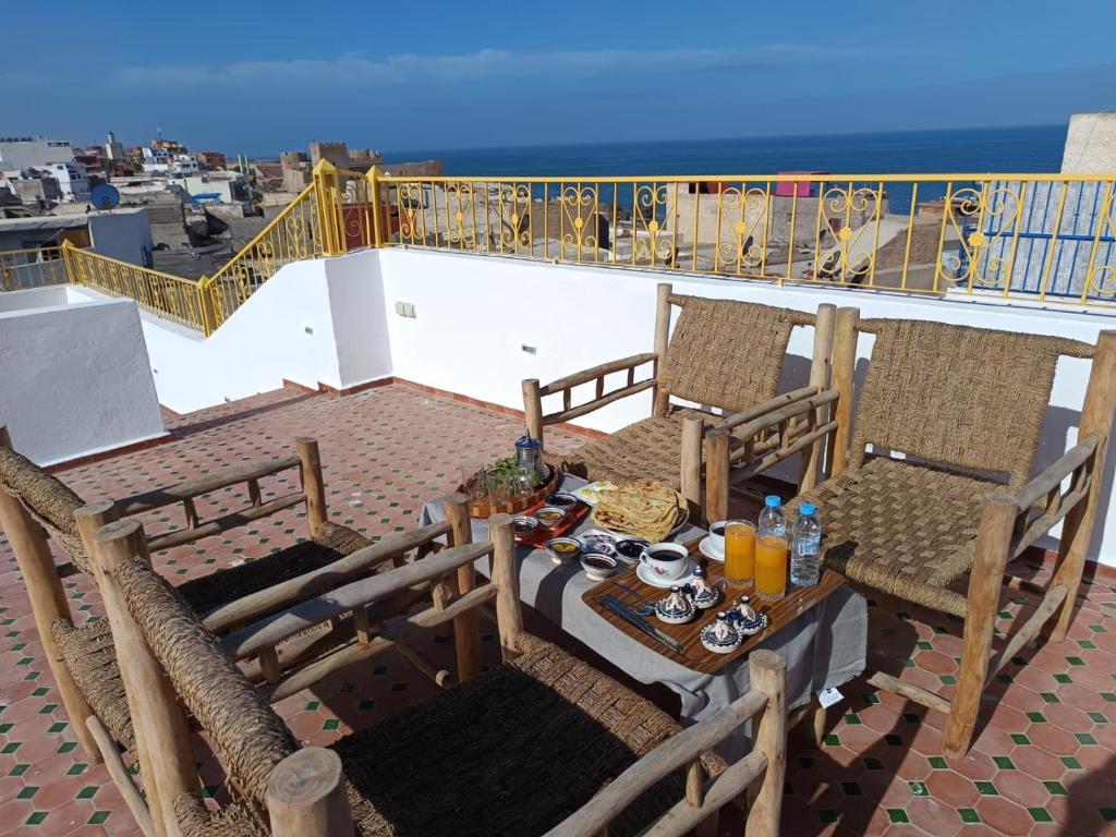 a table and chairs on a balcony with a view of the ocean at Dar Salam Asfi - Maison d'hôtes, terrasse vue Medina et océan in Safi