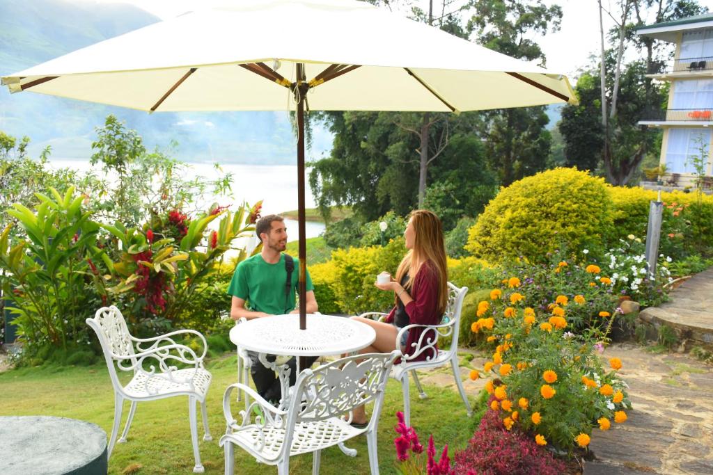 a man and woman sitting at a table under an umbrella at Hatton Summer House in Hatton