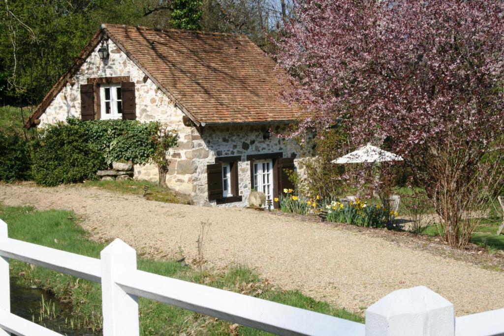 a stone house with a white fence in front of it at Au Moulin de La Gorce in La Roche-lʼAbeille