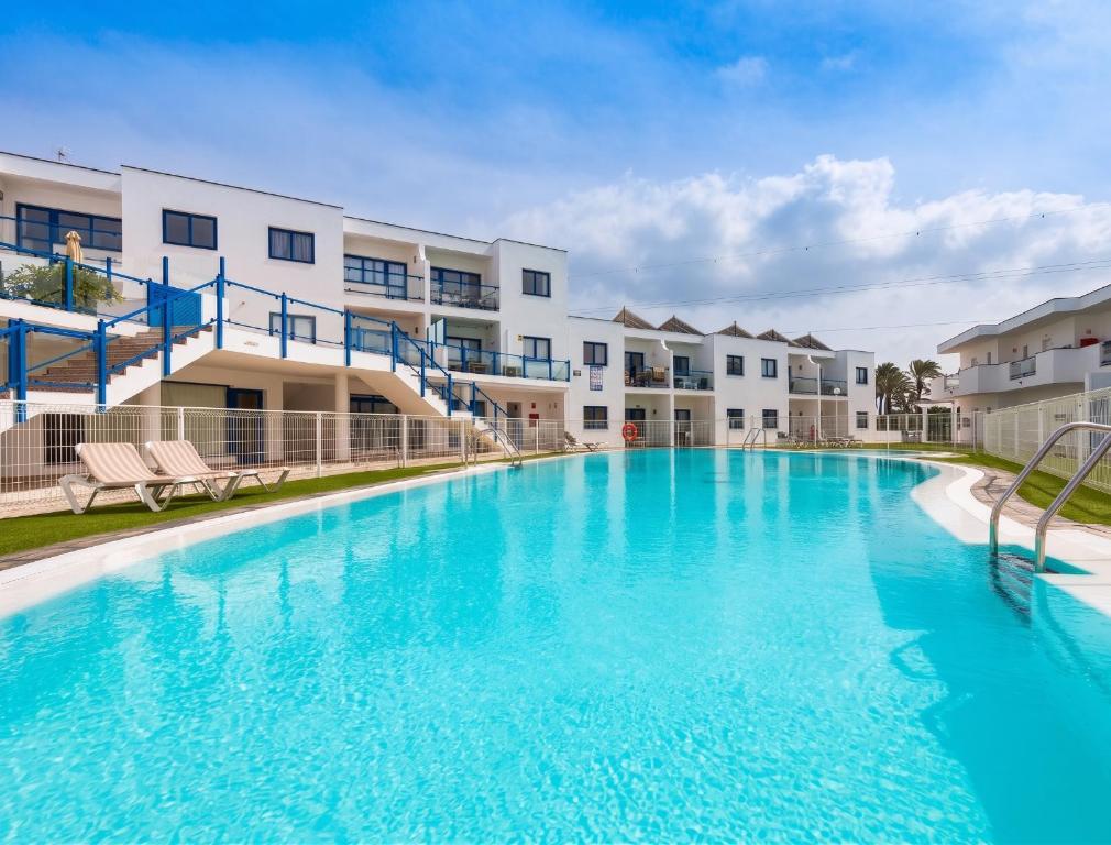 a large pool with blue water in front of apartment buildings at Home2Book Aloha Palm in Costa Calma