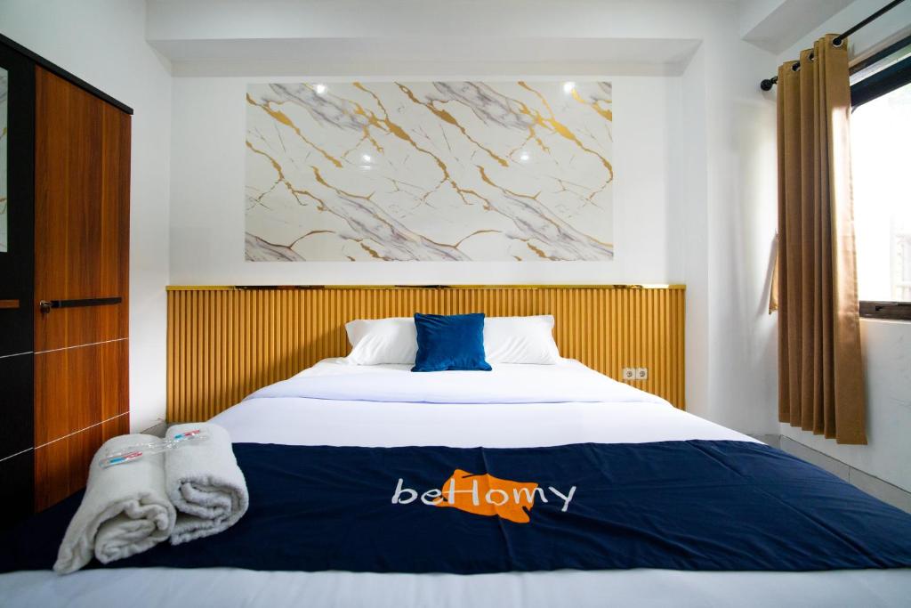 a bedroom with a large bed with blue and white sheets at Behomy J-Home Bandung in Bandung