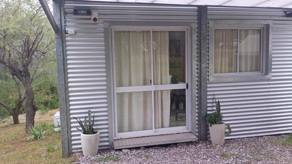 a house with two windows and two potted plants at La Dominga Tiny House in La Granja