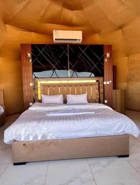 a bedroom with a large bed with a wooden headboard at Wadi Rum Luxury Hamad & Jeep Tours in Wadi Rum