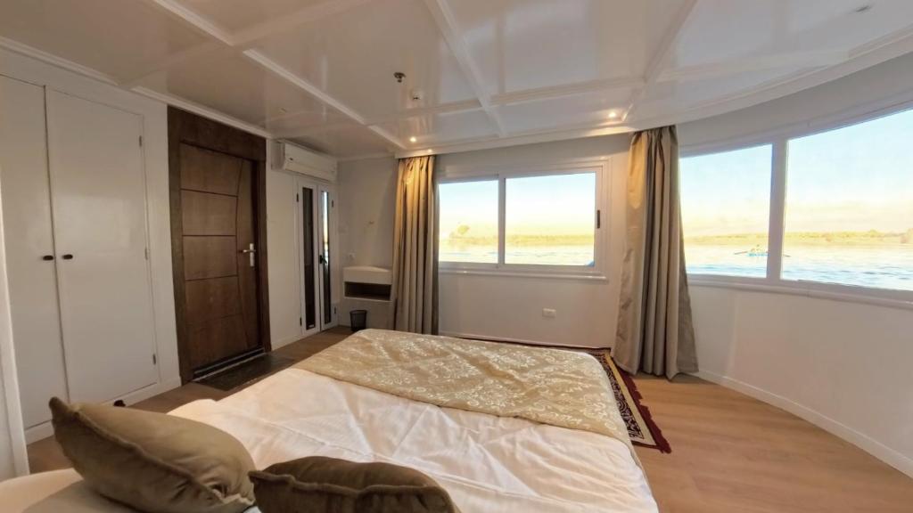 a bedroom with a large bed and a large window at The Nile Dahabiya Lodge in Luxor