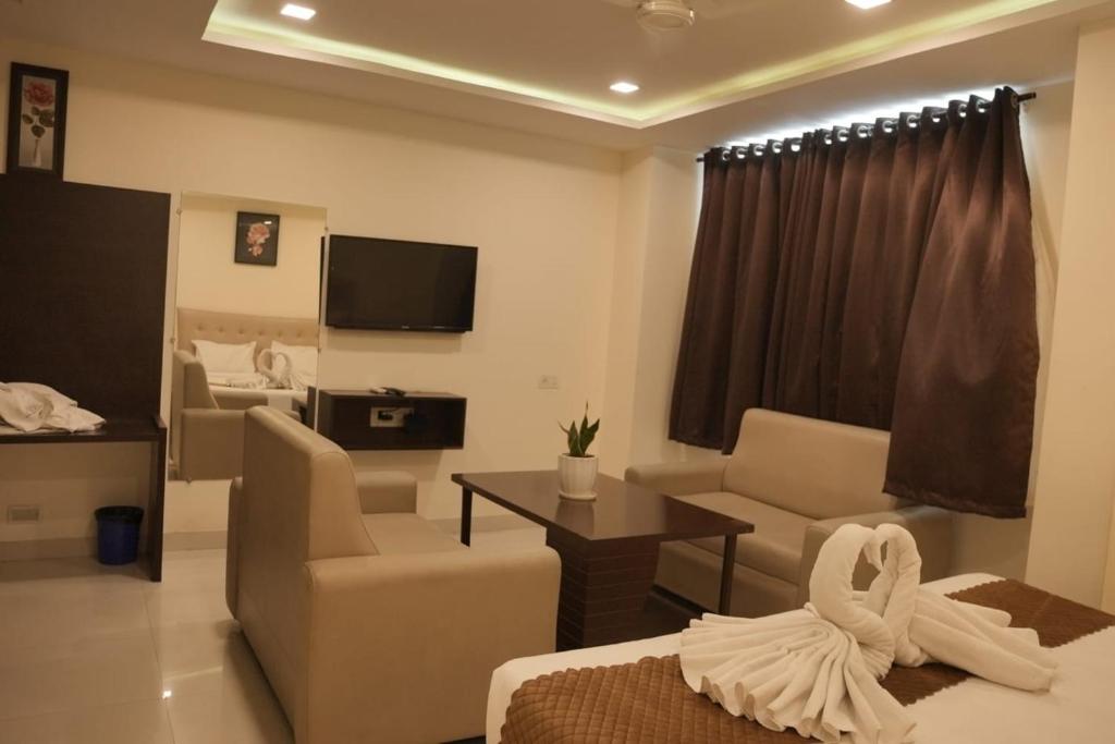 a living room with a couch and chairs and a tv at Hotel Surya Teja Priime in Khammam