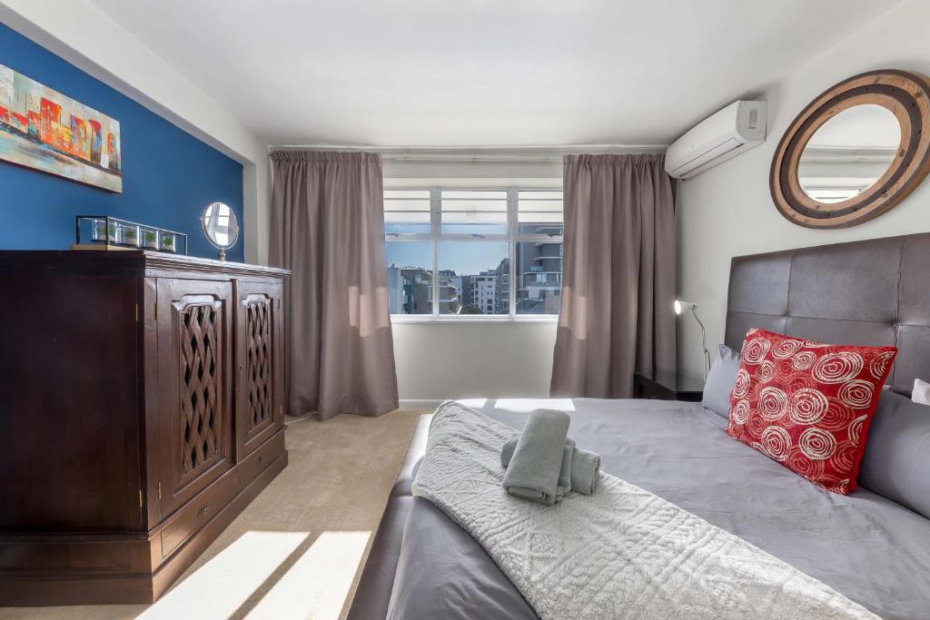 a bedroom with a large bed and a mirror at Comfy Central with Balcony and Views in Cape Town