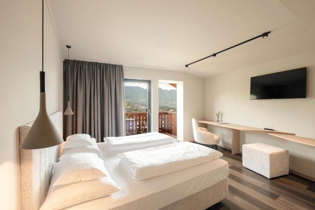 a white bedroom with a large bed and a desk at Hotel Öhlerhof in Lagundo