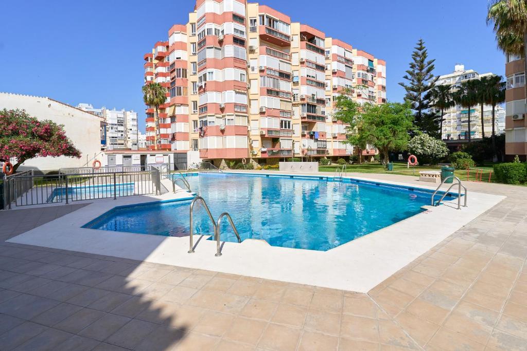 a swimming pool in front of a tall apartment building at Estudio Plazamar Palace in Torre del Mar