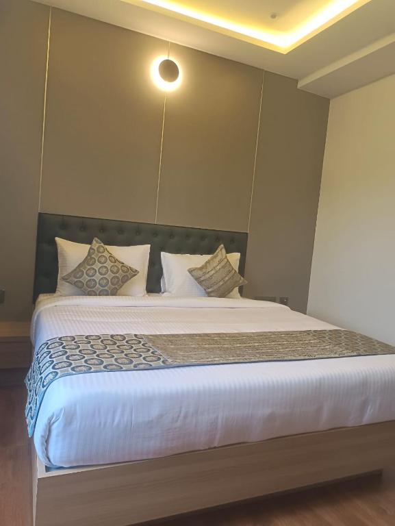 a bedroom with a large bed with white sheets and pillows at L G Cordial in Mysore