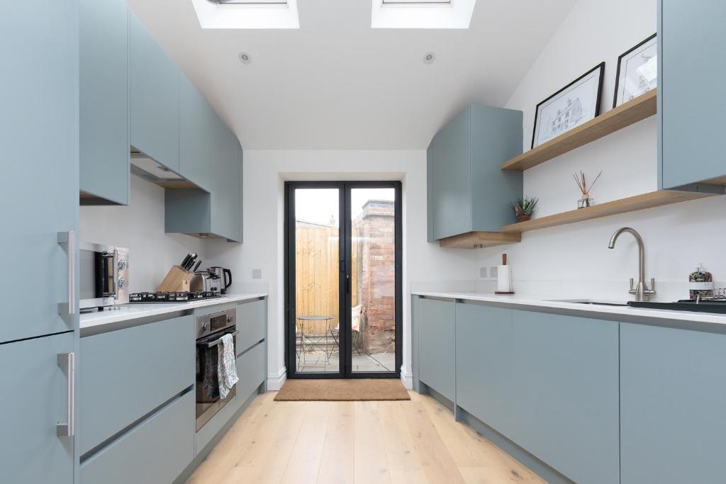a kitchen with blue and white cabinets and a doorway at Regent Street Residence Lutterworth in Lutterworth
