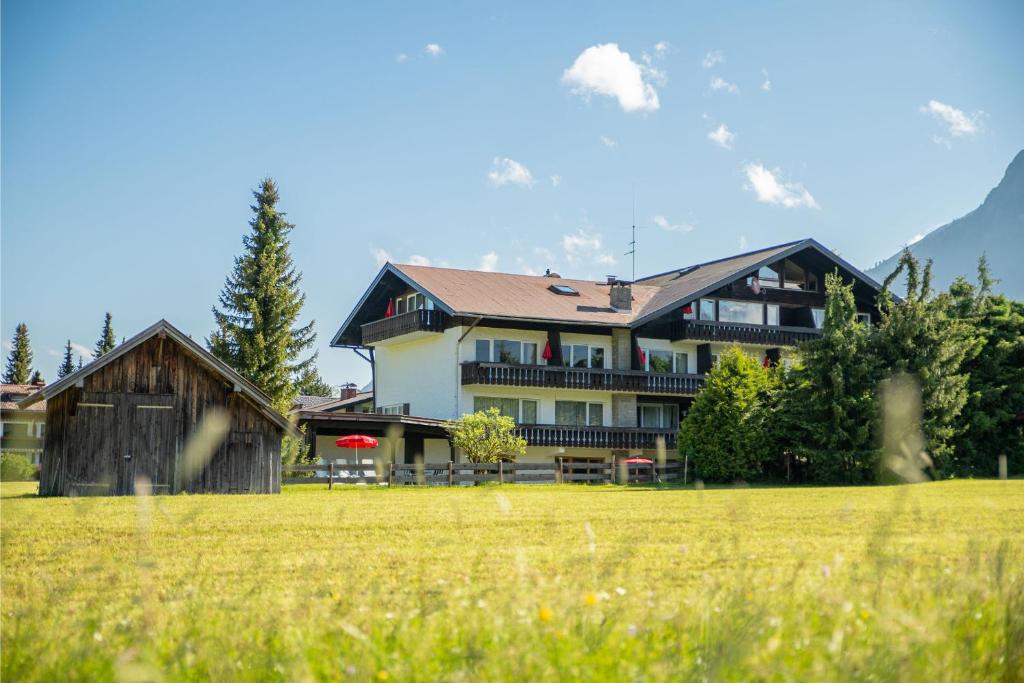 a large house with a field in front of it at Alpenhof Apartments Oberstdorf in Oberstdorf