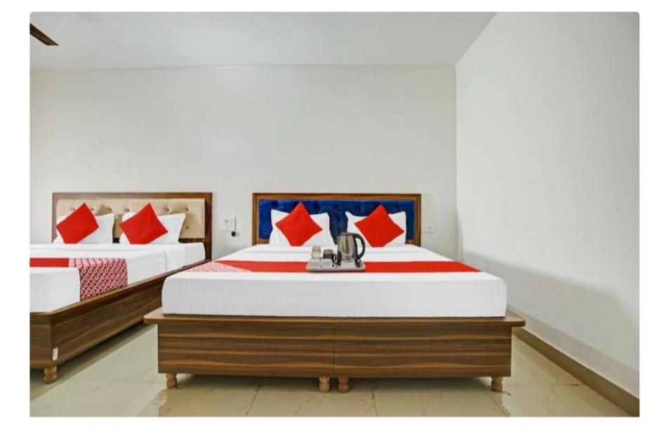 two beds with red and blue pillows in a room at Hotel R Himalayan in Mohali