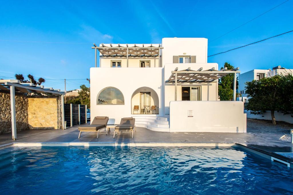 a villa with a swimming pool in front of a house at Naxos Infinity Villa and Suites in Naxos Chora