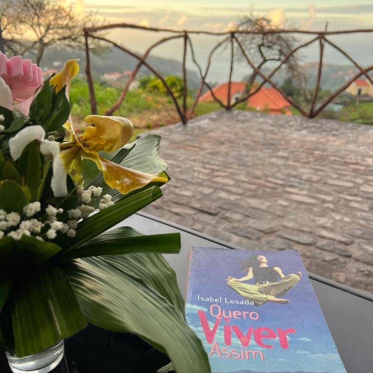 a book and a vase of flowers on a table at Cottagee Grandpa Silva in Santana