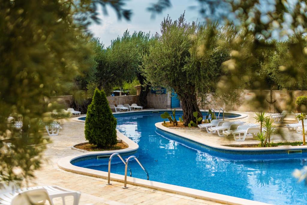a swimming pool with chairs and trees in a resort at Villa Ponta in Buljarica
