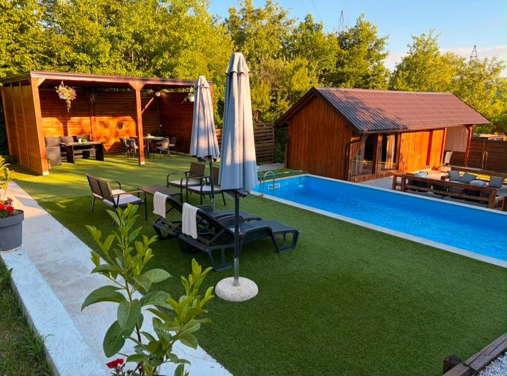 a backyard with a pool and an umbrella and chairs at Hellena in Sarajevo