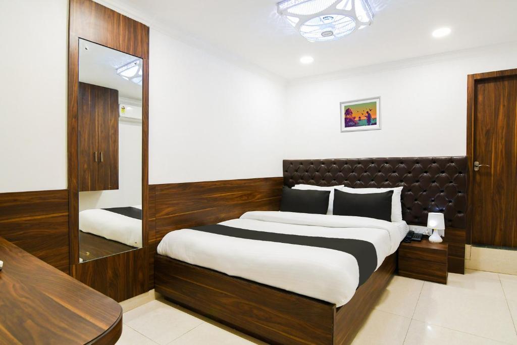 a bedroom with a large bed and a mirror at Super Hotel O Eminent Hotel in Kolkata