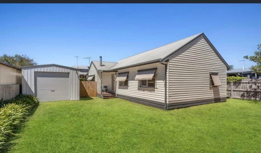 a house with a garage and a grass yard at Timber and Tide in Saint Leonards