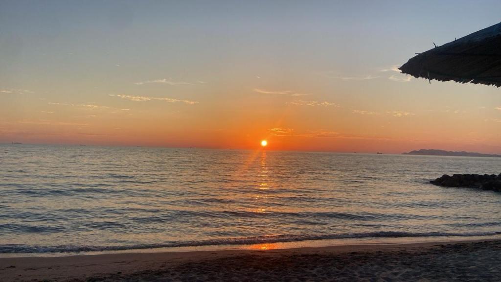 a sunset on the beach with the ocean at Bylis Rooms in Golem
