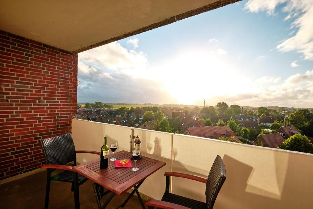 a table and chairs on a balcony with a view at FeWo Sonnenschein mit Pool & Balkon in Horumersiel