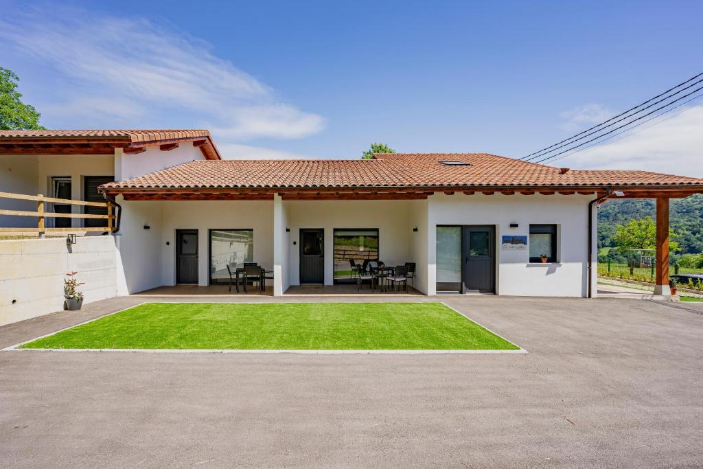 a house with a patio and a grass yard at Apartamentos el Caneyón in San Juan de Parres