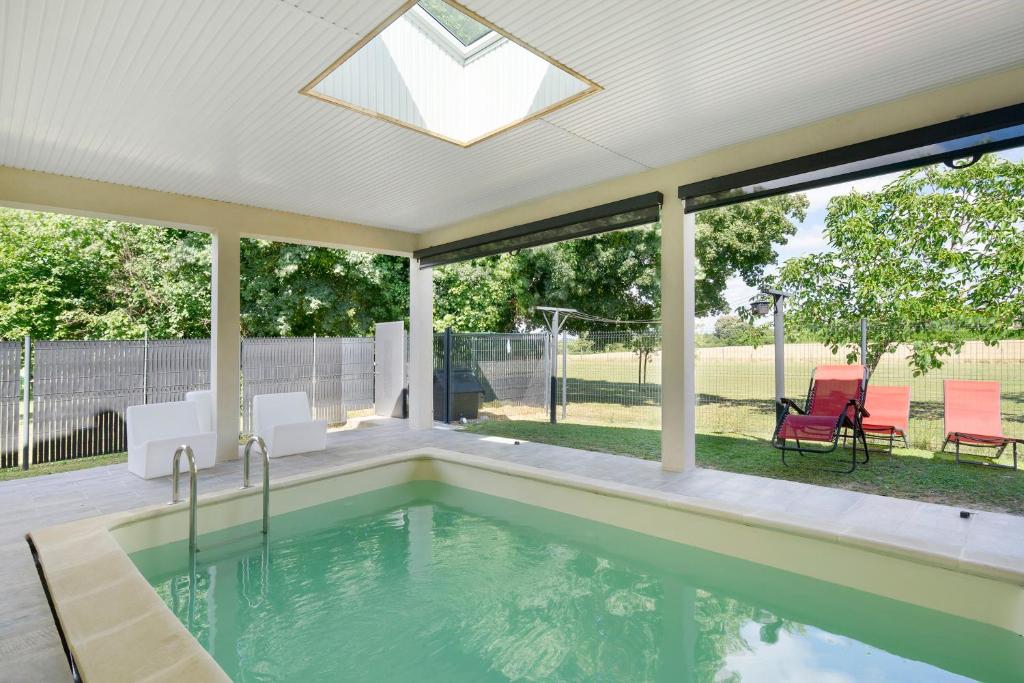 a swimming pool in a house with a large window at La Casa Andréa in Villars-en-Pons