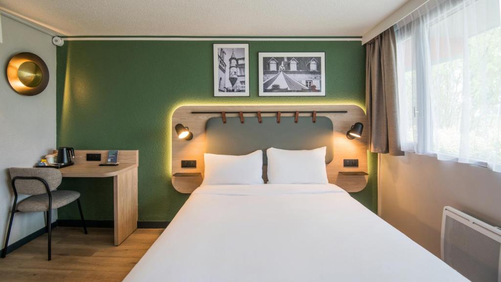a bed in a room with a green wall at Campanile NATURE - Brive-la-Gaillarde in Brive-la-Gaillarde