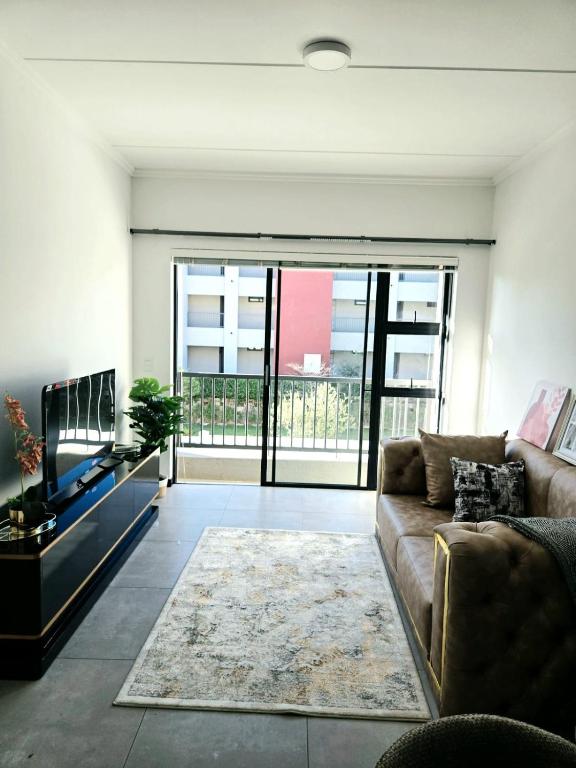 a living room with a couch and a large window at Royalty Suites in Chartwell Sandton in Chartwell