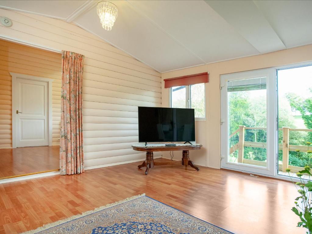 a living room with a flat screen tv and a table at 2 The Folly's - Uk45188 in Abbotskerswell