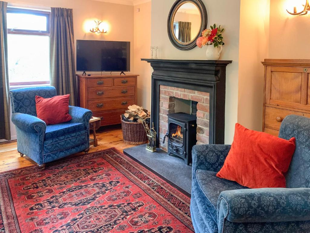 a living room with two chairs and a fireplace at Forester's Cottage in Kildary