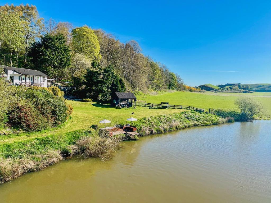 a river with a boat on the side of it at Harperfield Chalet in Lanark
