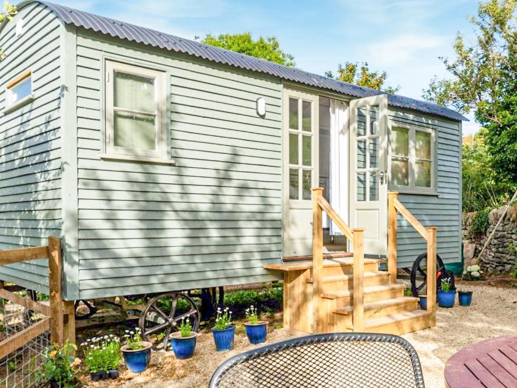 a tiny house with a staircase in a yard at Fig Tree Shepherds Hut in Bridport