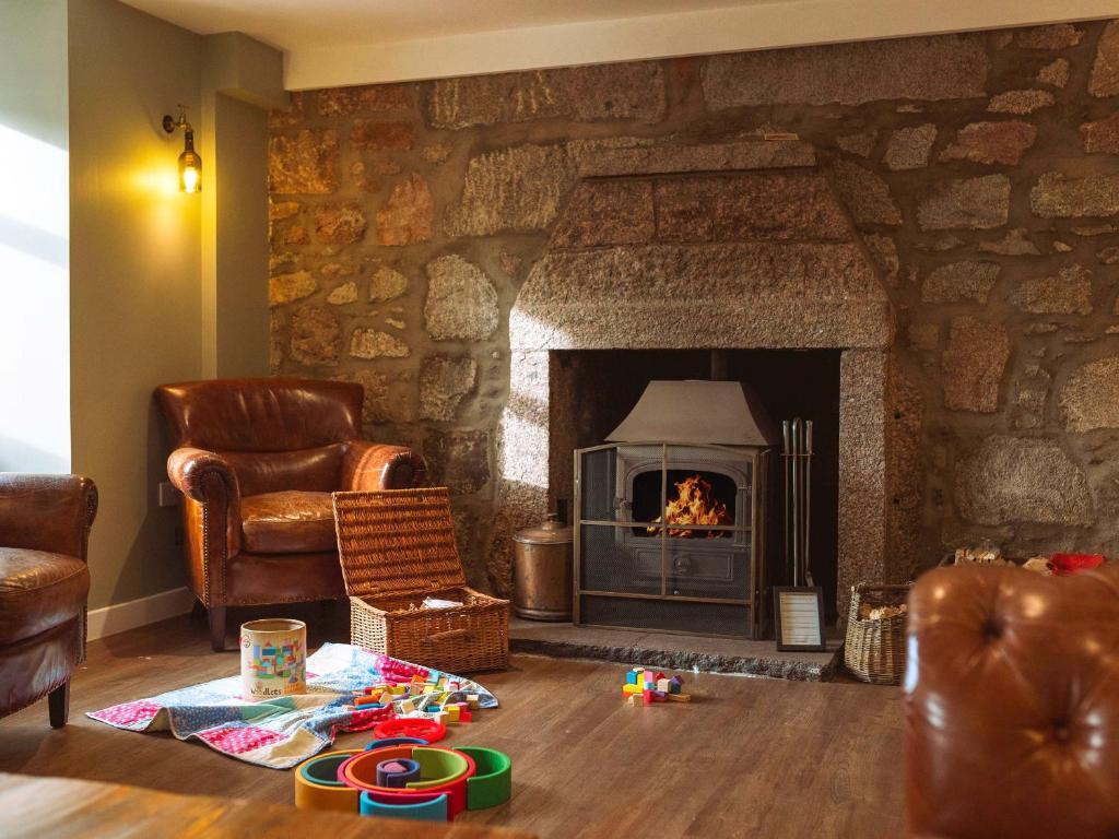 a living room with a stone fireplace and a chair at Potarch Lodge in Kincardine OʼNeil