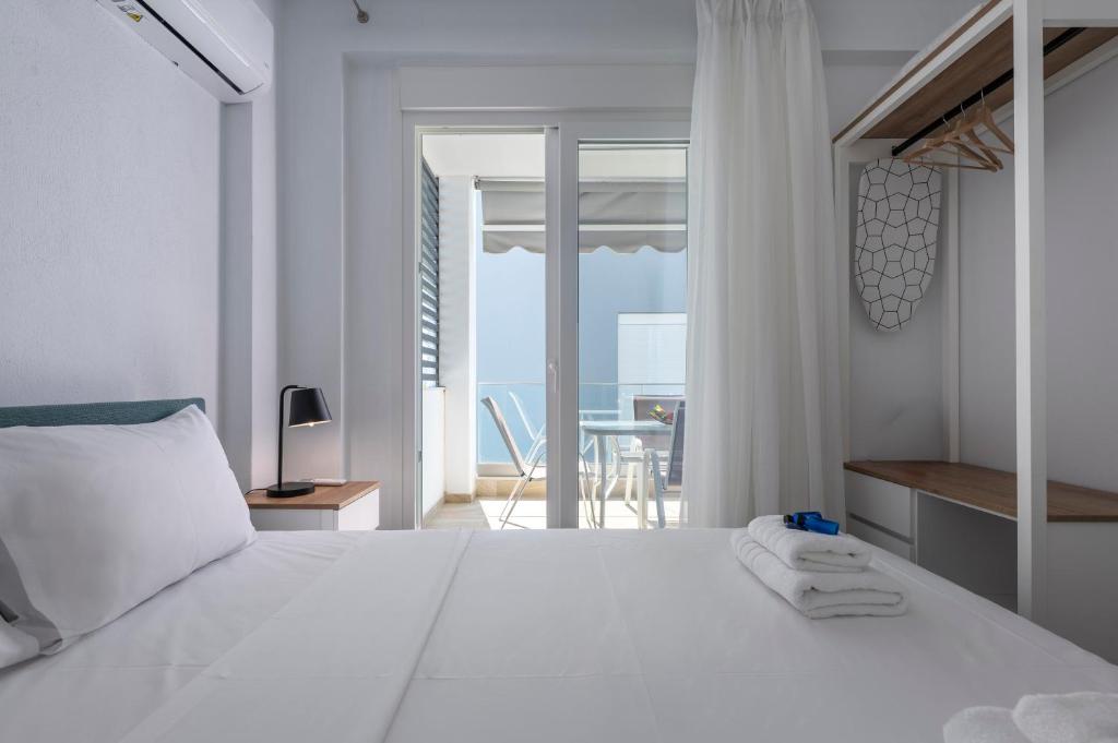 a bedroom with a white bed with a view of the ocean at SLV Roxani Apartment in Ofrínion