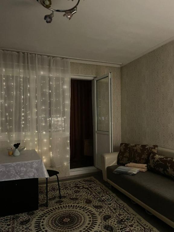 a living room with a couch and a window with lights at Piitota in Almaty