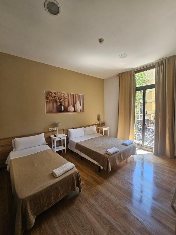 a bedroom with two beds and a large window at Hostal Delfos in Barcelona