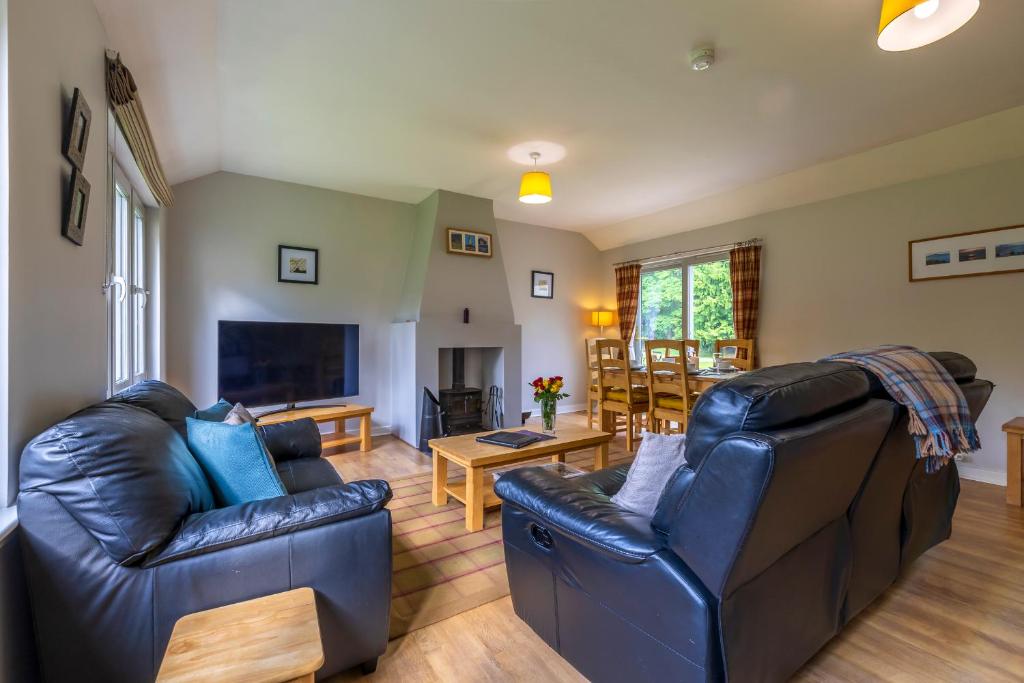 a living room with two leather chairs and a television at Loch Ness Abbey Cottages in Fort Augustus