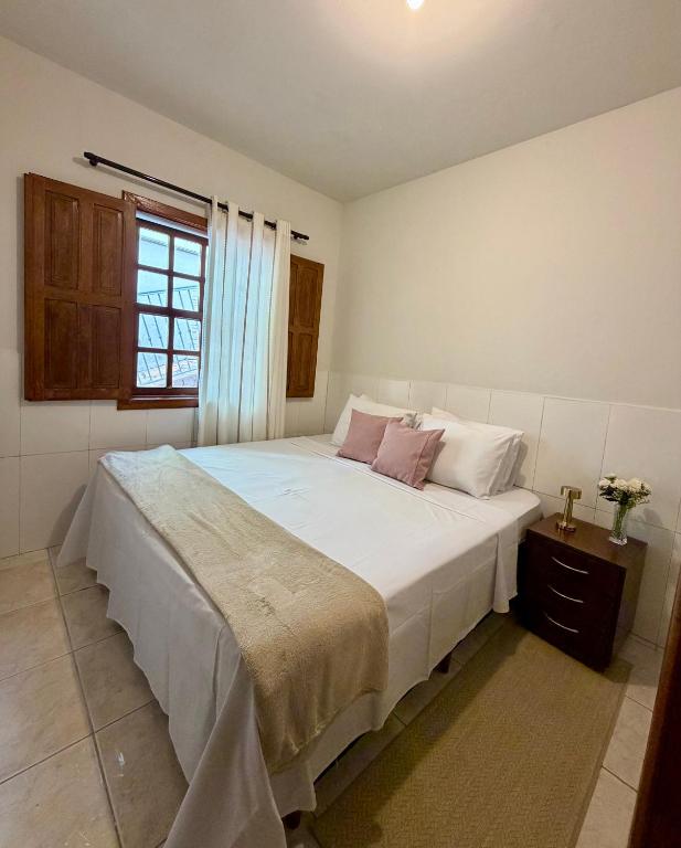 a bedroom with a large white bed with pink pillows at Recanto Canuto in Diamantina