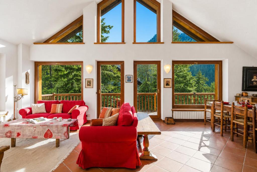 a living room with red furniture and large windows at Hostdomus - Chalet Claviere in Claviere