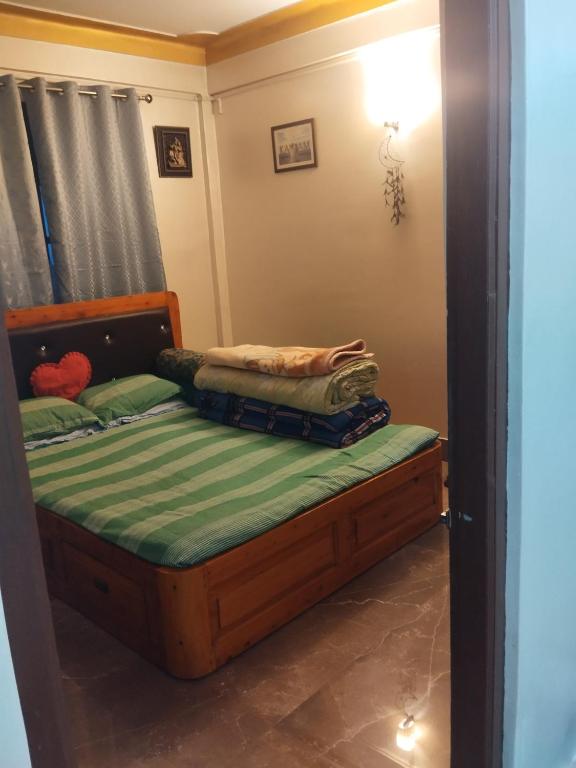a small bedroom with a bed with a green mattress at Laligurash in Mirik