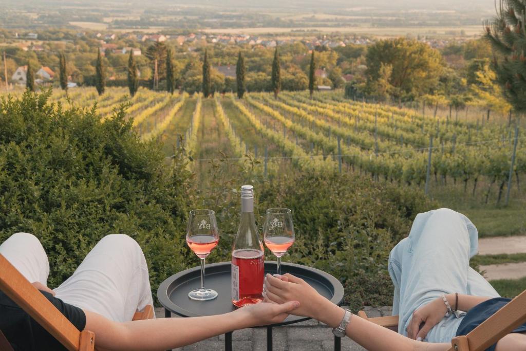 two people sitting at a table with glasses of wine at Villa Rustica Vendégház Sümeg in Sümeg