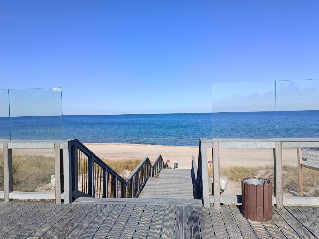 a wooden staircase leading to a beach with the ocean at Azyl in Darłówko