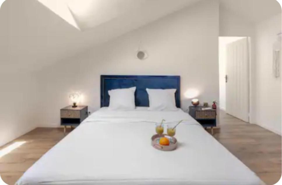 a large white bed with a bowl of fruit on it at Chambre Attrape rêves in Sainte-Geneviève-des-Bois